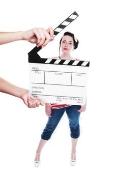 A clapper board being held up in front of a young actress dressed in rockabilly fashion.  Shot on white background.  Focus on clapper board.