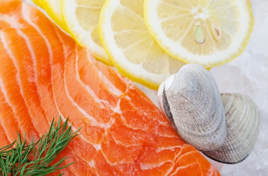 Raw seafood on a bed of crushed ice, garnished with slices of lemon and dill, ready for cooking.