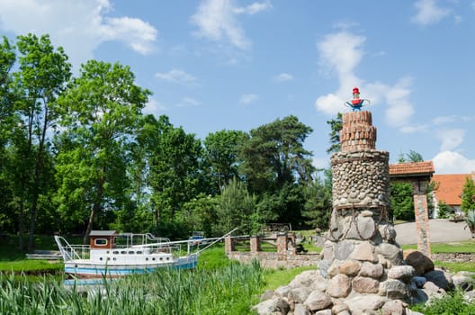 stylized stone lighthouse at the river with ancient tourist boat