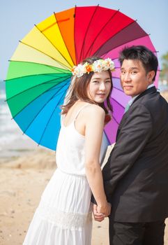 Beautiful asian couple on the beach in wedding dress