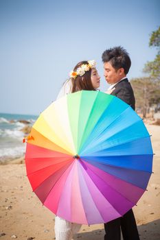 Beautiful asian couple on the beach in wedding dress