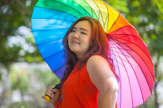 Happy fatty asian woman with umbrella outdoor in a park