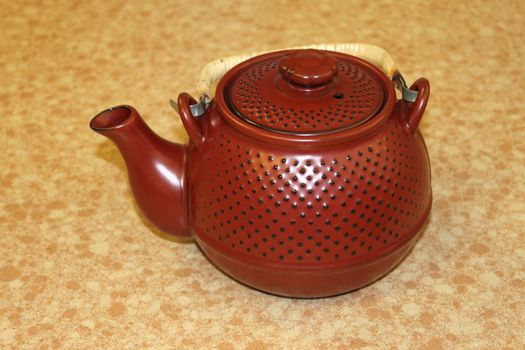 One small Japanese red teapot on a table.