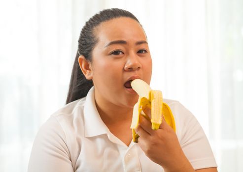 Fat asian woman with banana on white