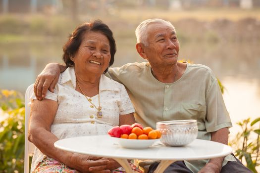 Happy Asian Senior couple sitting outdoors on sunset