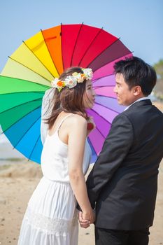 Beautiful asian couple on the beach in wedding dress