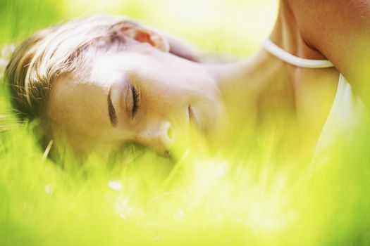 Beautiful young woman sleeping on grass outdoors