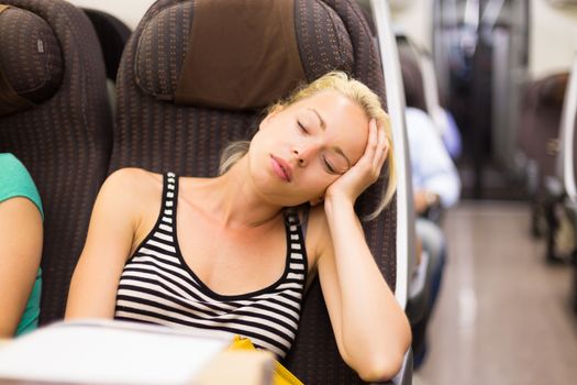 Blonde casual caucasian lady napping while traveling by train.