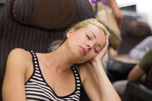 Blonde casual caucasian lady napping while traveling by train.