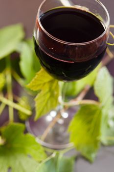 Red wine in glass with grape leaves