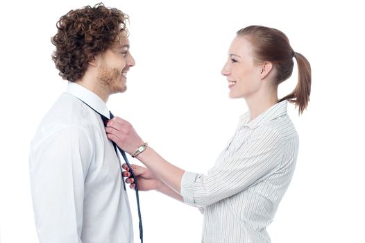 Smiling woman knotting the necktie of the businessman