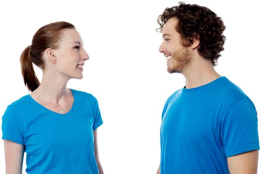 Smiling young couple in casuals, looking each other