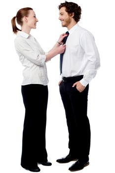 Young woman helping to knot her boyfriend's tie