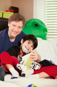 Handsome father playing cars with disabled son on floor mat