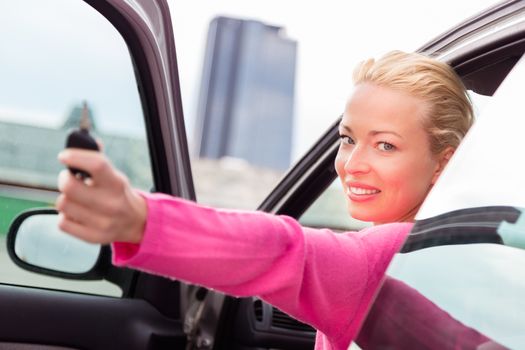 Woman driver showing car keys. Young female driving happy about her new car or drivers license. Caucasian model.