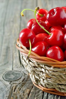 cherry in straw basket isolated on old wooden background