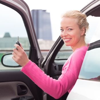 Woman driver showing car keys. Young female driving happy about her new car or drivers license. Caucasian model.