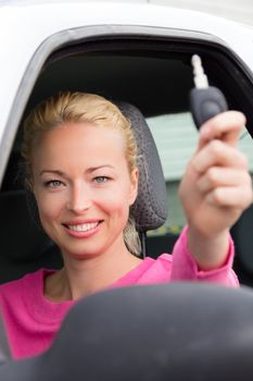 Woman driver showing car keys. Young female driving happy about her new car or drivers license. Caucasian model.