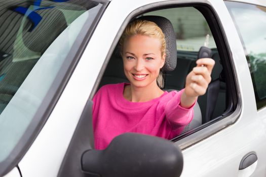 Woman driver showing car keys. Young female driving happy about her new car or drivers license. Caucasian model.