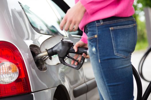 Closeup of woman pumping gasoline fuel in car at gas station. Petrol or gasoline being pumped into a motor vehicle car.