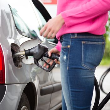 Closeup of woman pumping gasoline fuel in car at gas station. Petrol or gasoline being pumped into a motor vehicle car.