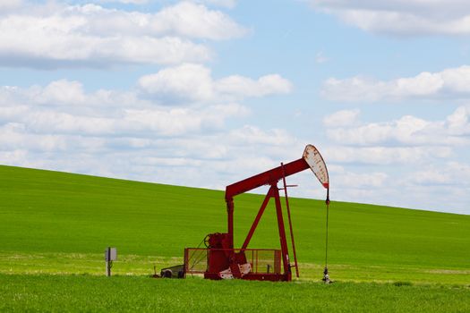 A pumpjack by a grassy hill. Alberta, Canada.