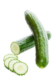 Two fresh English cucumbers, with one sliced.  Shot on white background.
