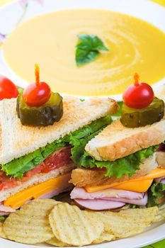 A delicious clubhouse sandwich, served with crunchy rippled potato chips and creamy butternut squash soup.