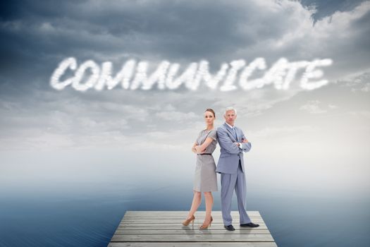 The word communicate and serious businessman standing back to back with a woman  against cloudy sky over ocean