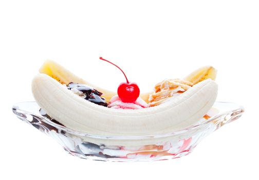 A scrumptious banana split, topped with caramel, strawberry, and chocolate, with a cherry garnish.  Shot on white background.