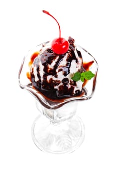A delectable, chocolate sundae, made with vanilla ice cream, chocolate syrup and garnished with a red cherry and a sprig of fresh mint.  Shot on white background.