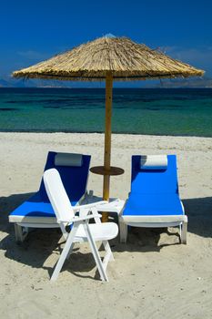 Colourful beach chairs with straw umbrellas on a beautiful sandy beach.