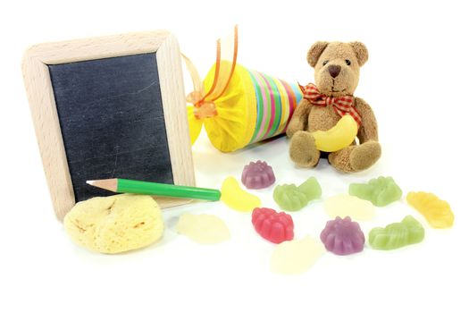 Teddy bear with school bag, wallet, sponge and blackboard on a light background