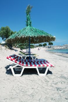 Relaxing sunbeds on the beach under straw umbrella.