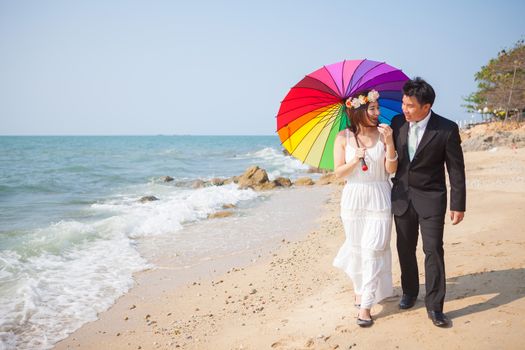 Beautiful asian couple on the beach in wedding dress