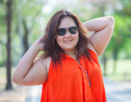 Happy fatty asian woman posing outdoor in a park