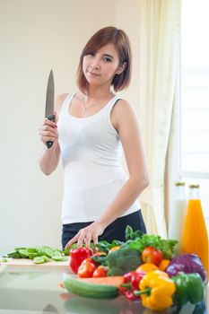 Happy asian woman cooking vegetables green salad in the kitchen