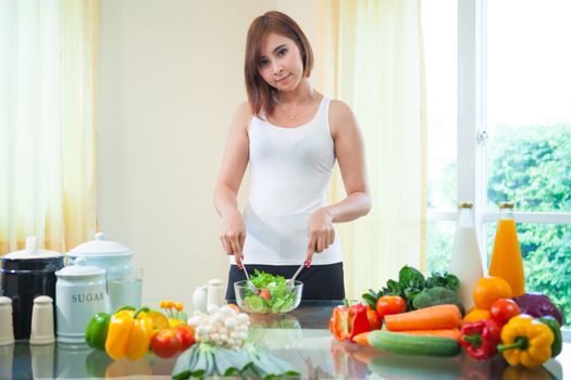 Happy asian woman cooking vegetables green salad in the kitchen