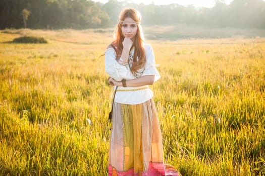 Hippie woman posing in golden field on sunset