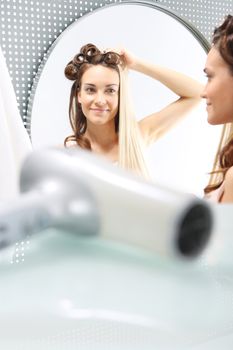 Woman with hair standing in front of a mirror. Changing hair color. Full colored hair.