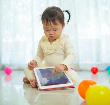 Happy little asian girl using tablet in the home