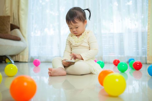 Happy little asian girl using mobile phone in the home