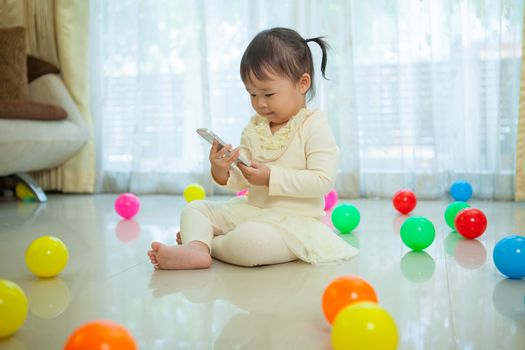 Happy little asian girl using mobile phone in the home