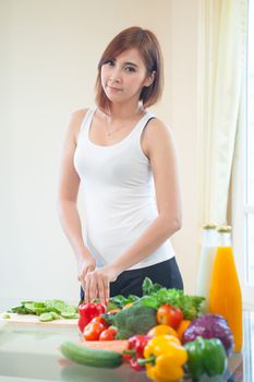 Happy asian woman cooking vegetables green salad in the kitchen