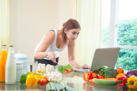 Young asian woman looking for a recipe on the internet in kitchen