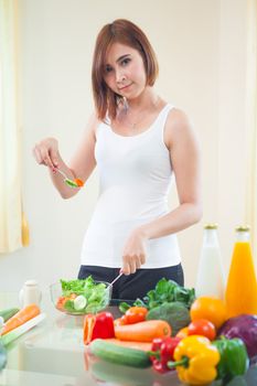 Happy asian woman cooking vegetables green salad in the kitchen