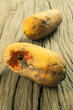 Closeup of moldy papaya fruit on wood background