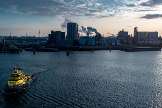 ROTTERDAM, NETHERLANDS - MAY 30, 2014: A tugboat is approaching the viewer in the port of Rotterdam on May 30, 2014 in Rotterdam, the Netherlands. With about 105 square kilometres and a stretch of about 40 km, Rotterdam is the largest sea port in Europe.