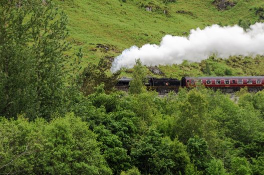 GLENFINNAN, SCOTLAND - June 5, 2014: A steam train on famous Glenfinnan viaduct, well known through Harry Potter as Hogwarts Express on June 5, 2014 in Glenfinnan, Scotland, Great Britain.