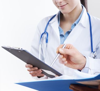 Young female practitioner and senior doctor checking medical records on a clipboard.